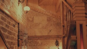 Un escalier en bois, avec un mur de briques d’un côté et un mur de pierres de l’autre.
