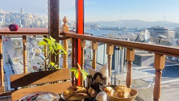 Ein Balkon mit Blick auf die Stadt, Holzmöbel und verschiedene Speisen.