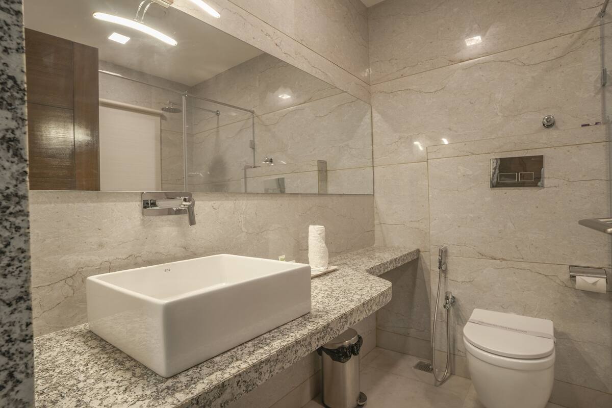 Une salle de bain moderne avec un lavabo rectangulaire, des toilettes, une douche et un miroir.