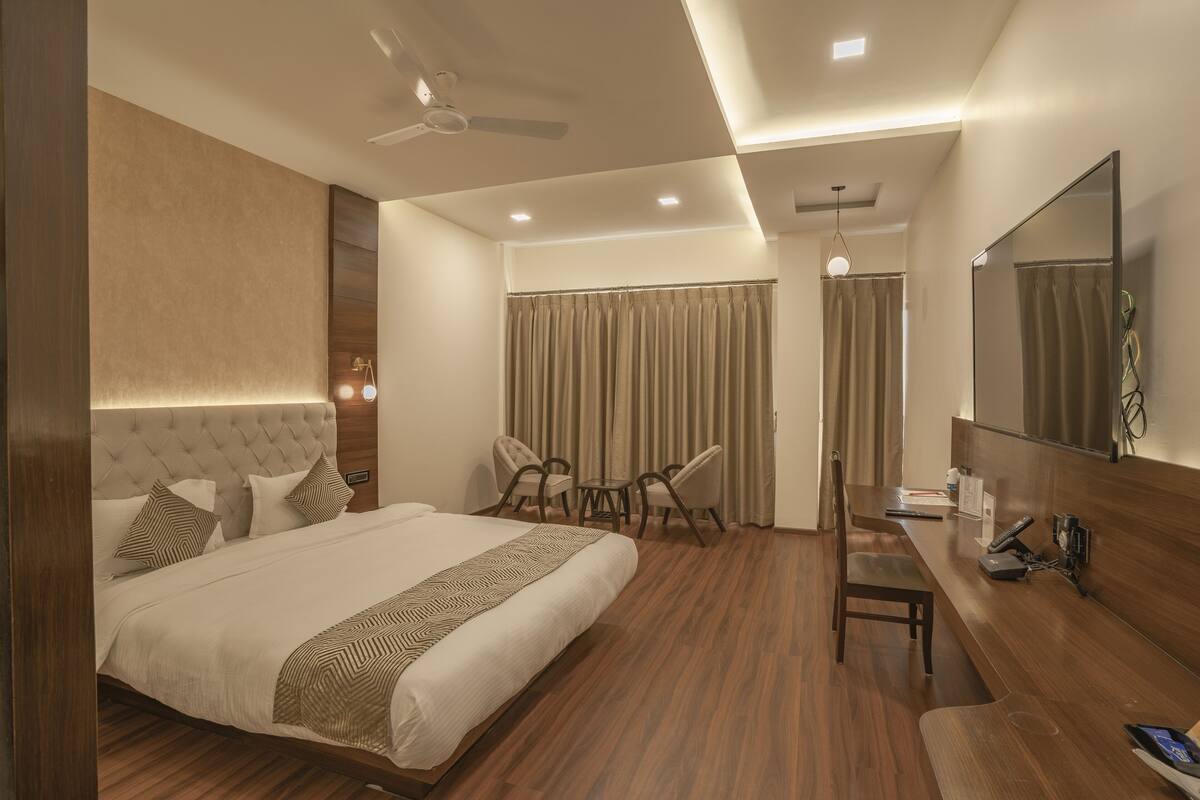 Une chambre d’hôtel moderne dotée d’un grand lit, d’un bureau avec une chaise, d’un ventilateur de plafond et d’un grand miroir.