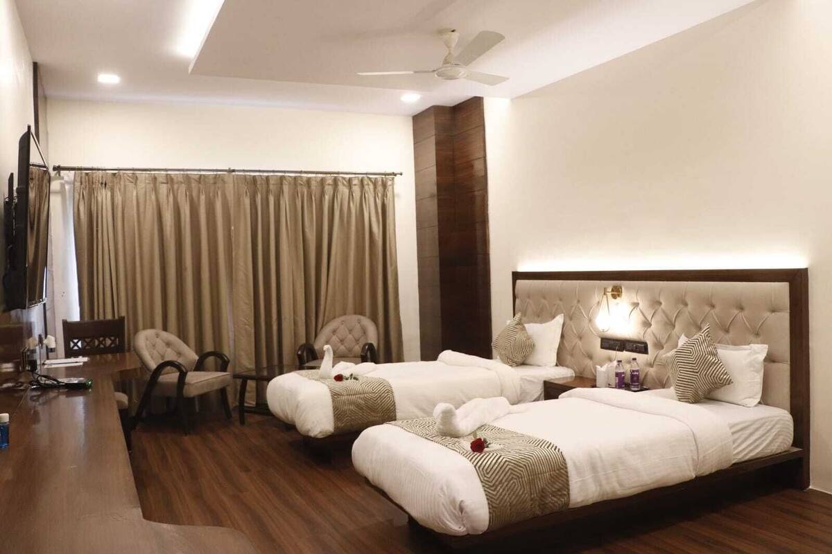 Une chambre d’hôtel avec deux lits, une télévision, un bureau et une chaise.