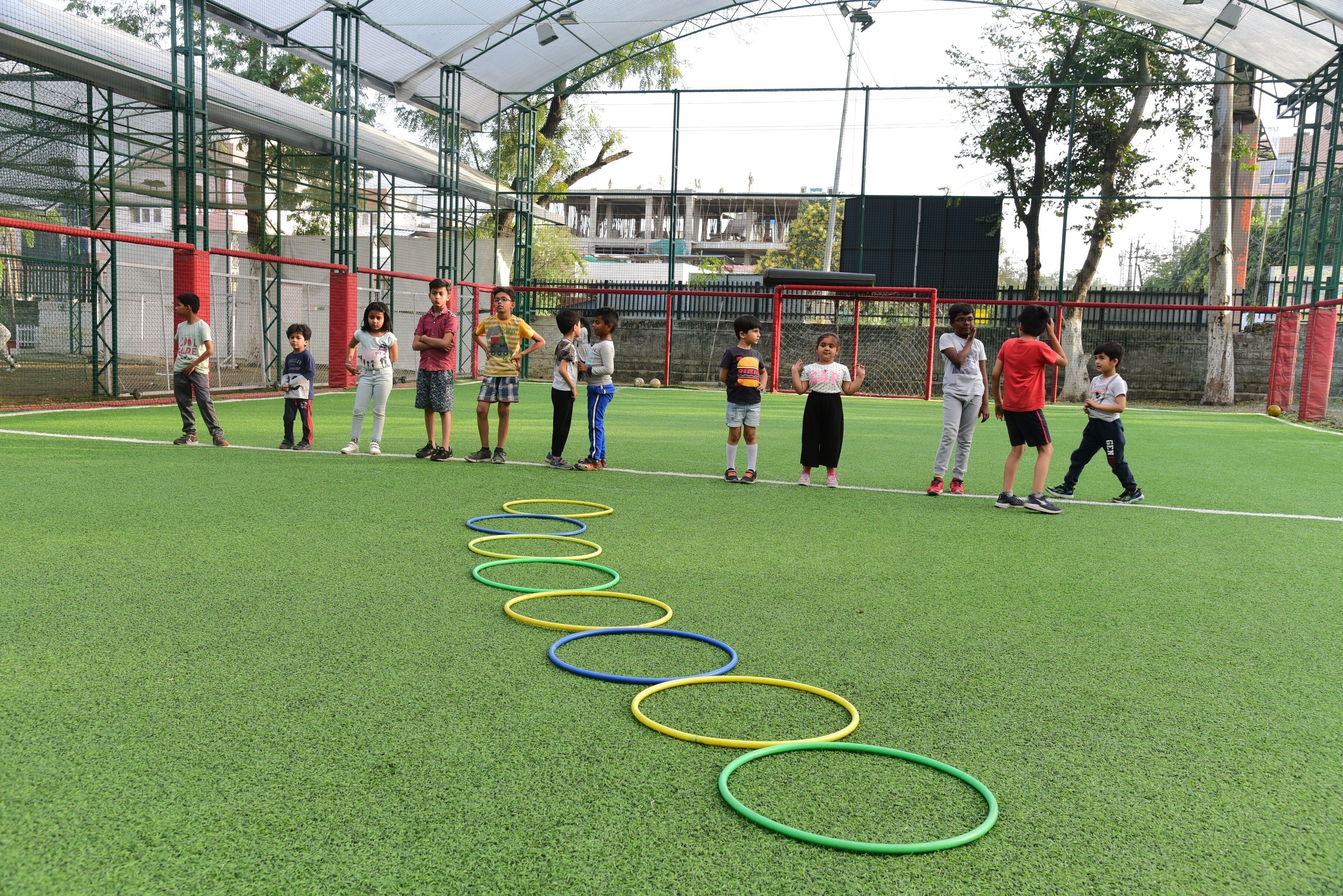 A group of children playing with hula hoops on a green artificial turf field.