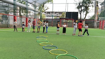 A group of children playing with hula hoops on a green artificial turf field.