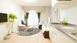 A modern apartment with a dining area, a sofa, a small kitchen, and a potted plant. - Asakusa Hotel 301 (Tokyo)
