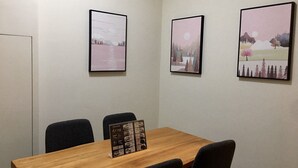 A meeting room with a wooden table, black chairs, and three framed artworks on the wall. - Yung Cheng (Jinhu)
