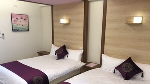 A hotel room with two beds, each with white bedding and purple accents. There are wall-mounted light fixtures and a painting of birds on the wall. - Yung Cheng (Jinhu)