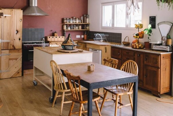 Une cuisine dotée d’un îlot central, de chaises en bois, d’une cuisinière et d’une fenêtre laissant entrer la lumière naturelle.