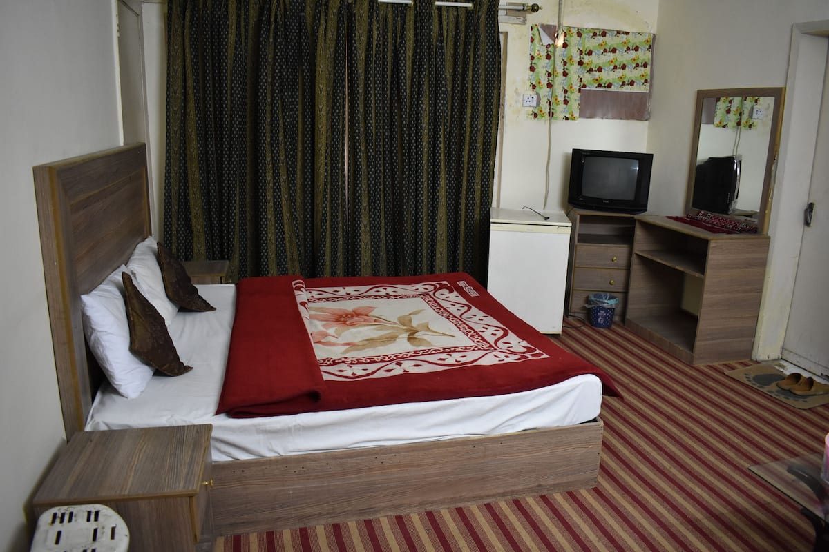 Ein Schlafzimmer mit Bett, Fernseher, Schreibtisch und Spiegel.