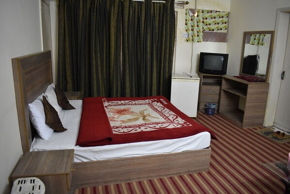 Une chambre à coucher avec un lit, une télévision, un bureau et un miroir.