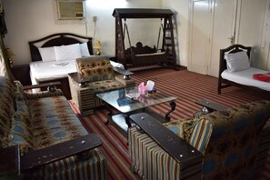 Une chambre traditionnelle comprenant un lit, un canapé, un fauteuil, une table avec un plateau en verre et un lit suspendu.