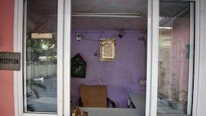 A reception area with a purple wall, a reception desk, a chair, and a framed picture on the wall. - Grand Inn Guest House (Islamabad)