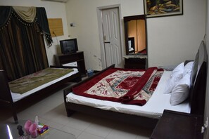 Ein Schlafzimmer mit zwei Betten, einem Fernseher, einem Kleiderschrank und einem Bild an der Wand.