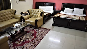 A hotel room with a sofa, armchair, and a bed with a headboard. - Grand Inn Guest House (Islamabad)