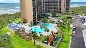 Un hotel con varias piscinas, zona de juegos infantiles y vistas al océano.