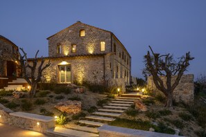 A stone house with a stone staircase leading to the entrance, surrounded by dry vegetation and rocks. - Locanda dei Logi (San Gimignano)