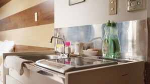 Una cucina con lavello in acciaio inossidabile, piano di lavoro bianco e parete rivestita in legno.