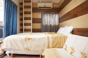 A bedroom with a bed, a window with curtains, an air conditioning unit, and a wooden wall panel.