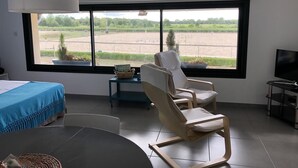 Quarto moderno com uma janela grande, uma cama, uma mesa de jantar e duas cadeiras.