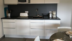 Uma cozinha moderna com micro-ondas, torradeira, pia e cafeteira.
