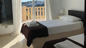 A hotel room with a bed, a small bedside table with a lamp, a window with curtains, and a view of a cityscape. - Villa Zoe - 4 bed - sleeps 8 - sea views - BOOK NOW!!!! (Benitachell, Alicante)
