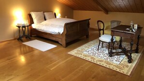 Ein Schlafzimmer mit einem hölzernen Bett, Nachttischen, einem Schreibtisch und einem Stuhl.