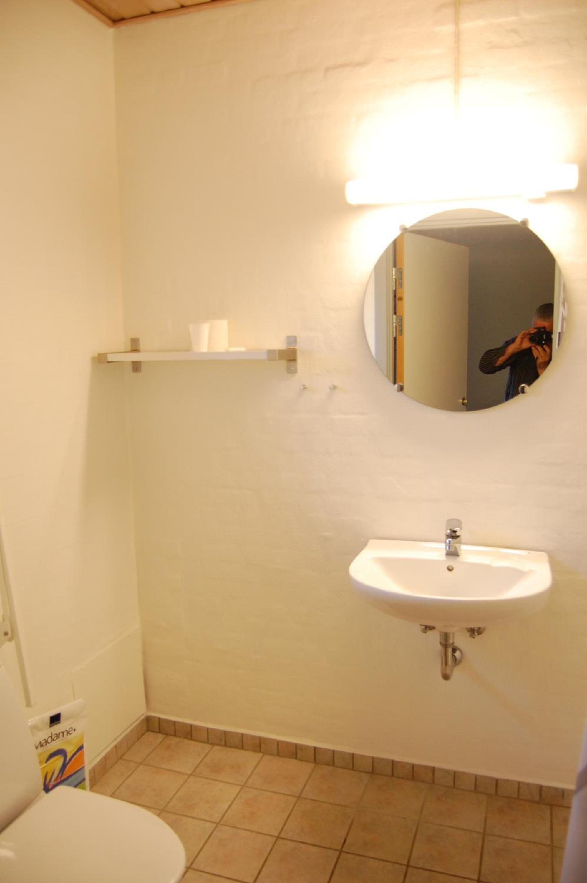 Un baño con un lavamanos blanco, un espejo y un inodoro.