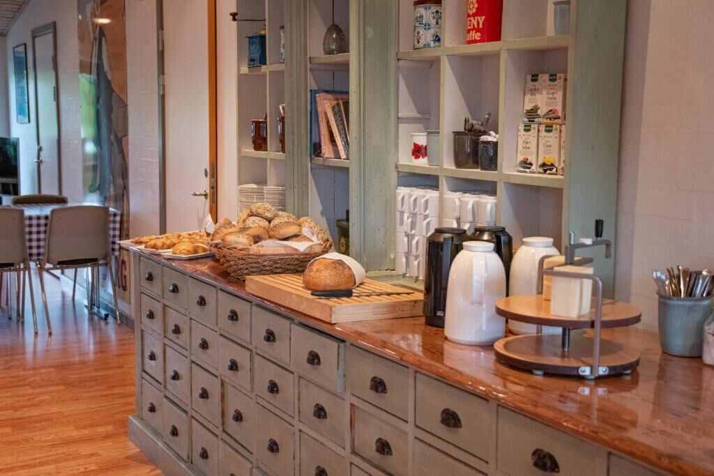 A breakfast bar with bread, pastries, and coffee-making equipment.