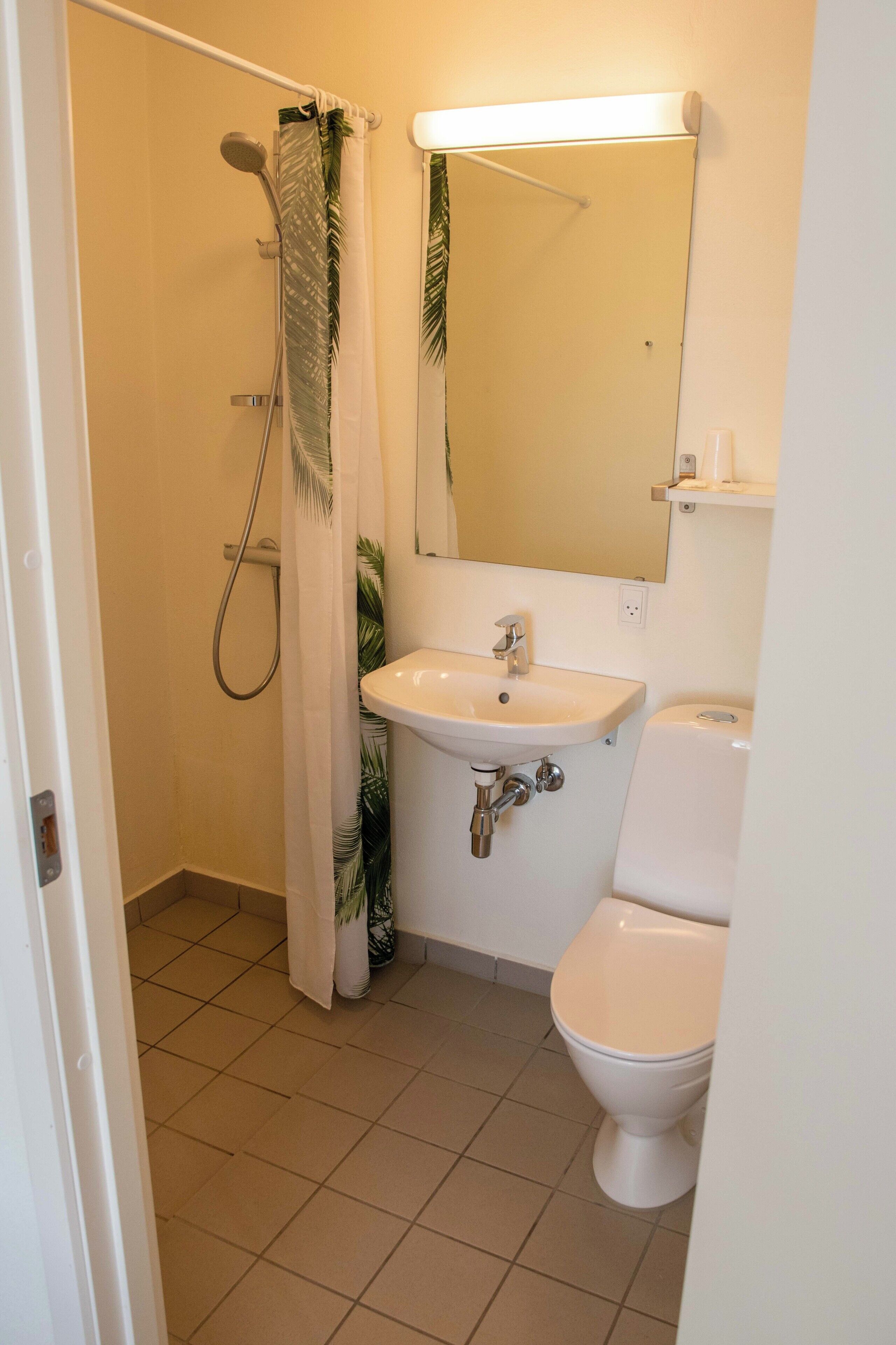 A bathroom with a shower, sink, and toilet.
