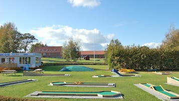 Un campo de prácticas de golf con múltiples calles verdes, un área de picnic y un pequeño edificio con la inscripción 'Isbar'.