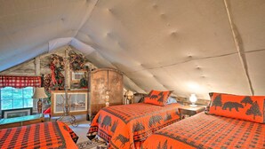 Una camera da letto mansardata accogliente con due letti, un'armadietto in legno e una finestra vista.