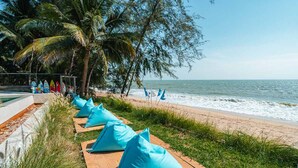 Un'area relax in spiaggia con cuscini blu e tavole da surf.