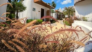 Un resort con edifici bianchi, tetti di paglia e palme.