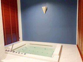 Un baño moderno con una bañera independiente, persianas de madera y una pared azul de acento.