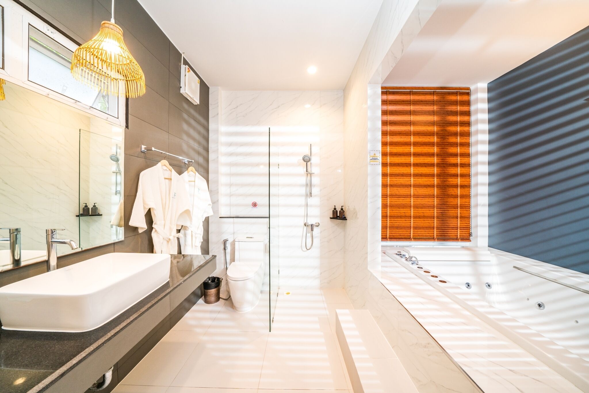 A modern bathroom with a large white sink, a glass-enclosed shower, and a wooden panel wall.