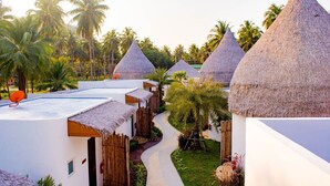 Un resort con capanne a tetto di paglia, un vialetto e palme.