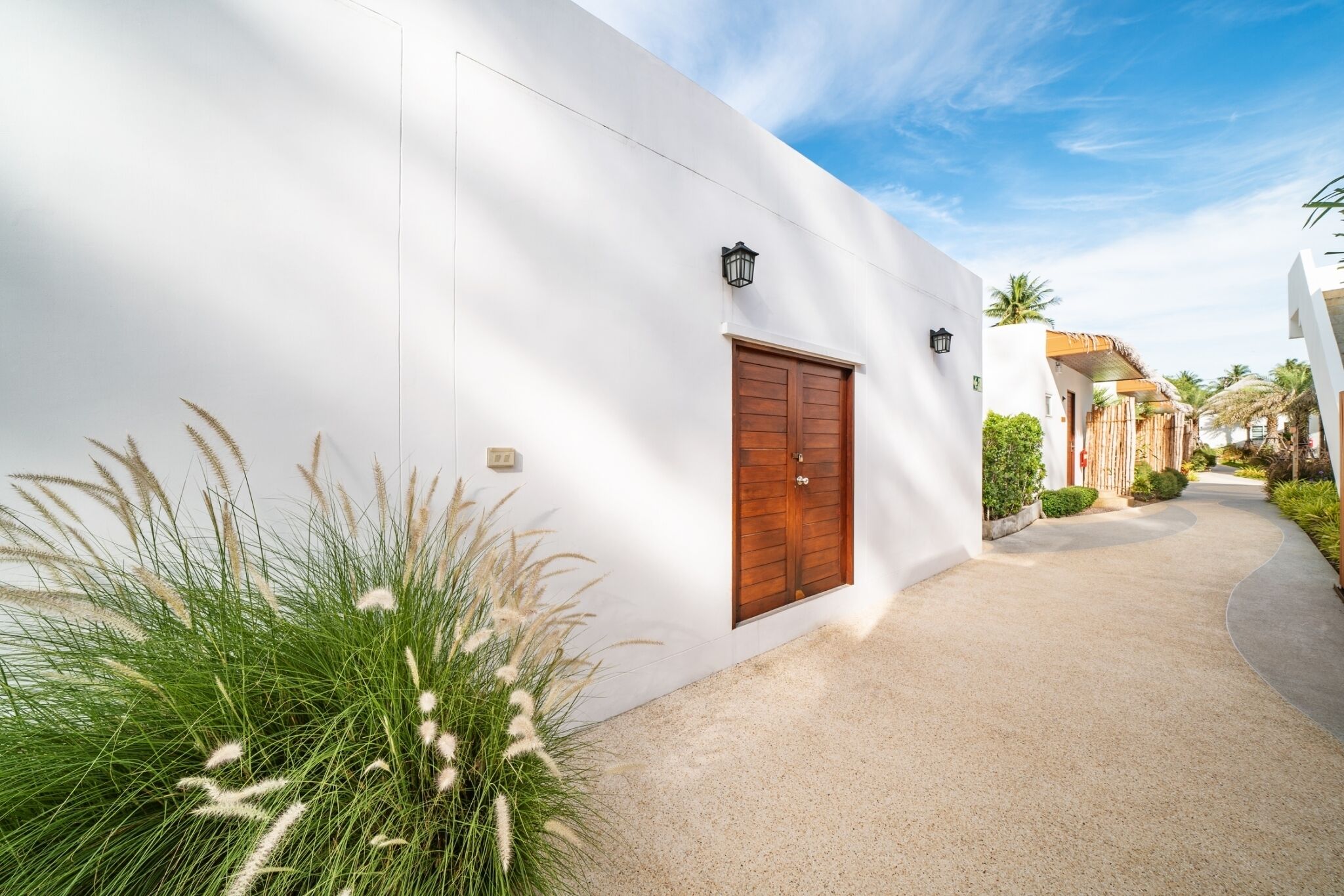 A white building with a wooden door and a small lamp on the wall.