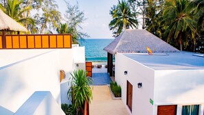 Un resort con un edificio a tetto di paglia, una piscina e vista sull'oceano.