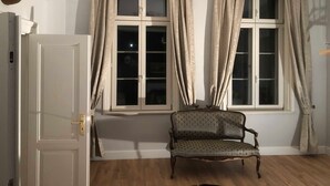 A room with a patterned armchair, a chandelier, and a deer head decoration. - Hirschaue - Redentin manor house (Krusenhagen)