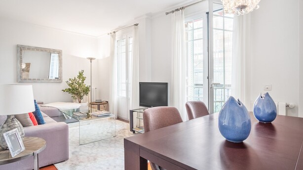 Uma sala de estar moderna com sofá, mesa de centro, TV e mesa de jantar com cadeiras.
