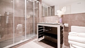 Une salle de bain moderne avec une douche à parois de verre, un lavabo blanc et des toilettes.