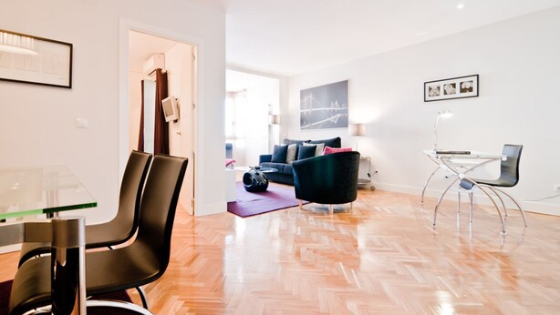 Un salon moderne comprenant un canapé, une table basse et un coin repas avec des chaises et une table en verre.