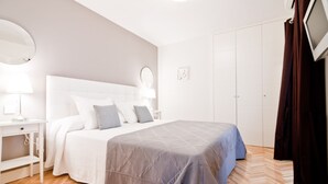 Une chambre à coucher comprenant un lit, des tables de chevet, un miroir, une armoire et un téléviseur.
