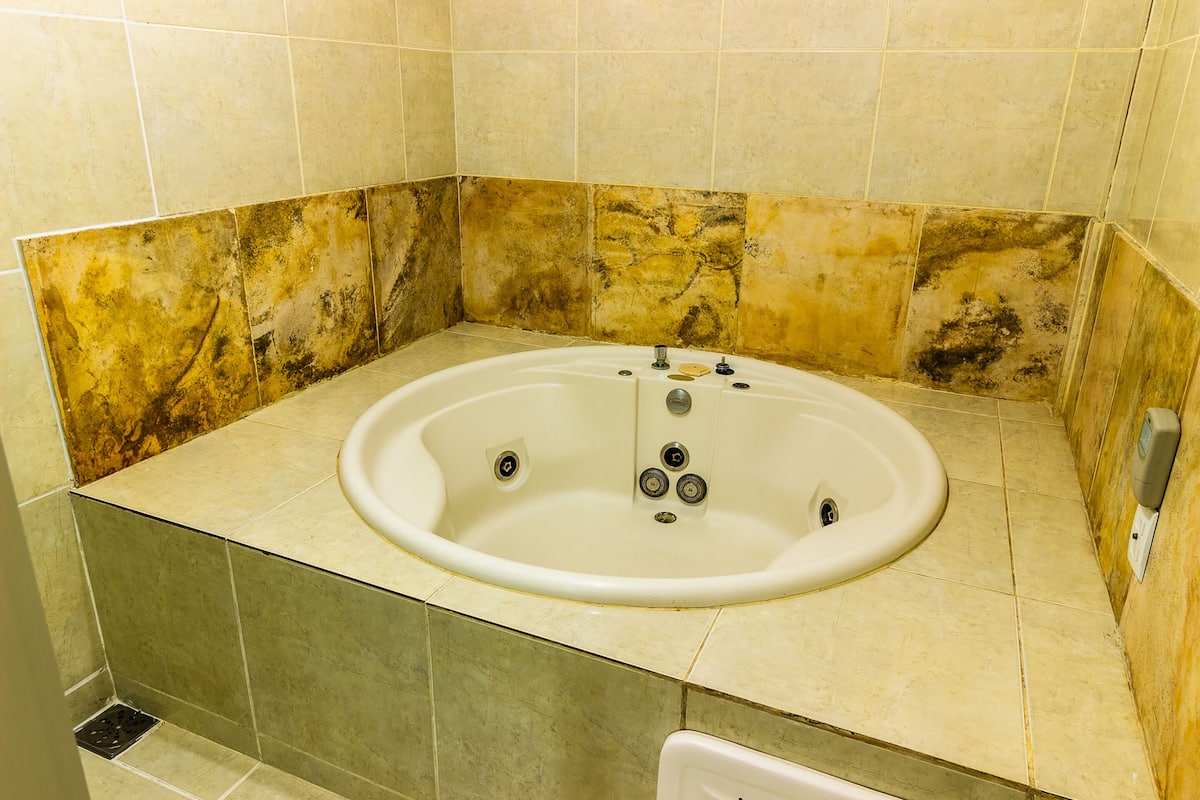 A bathroom with a bathtub, tiled walls, and a shower drain.