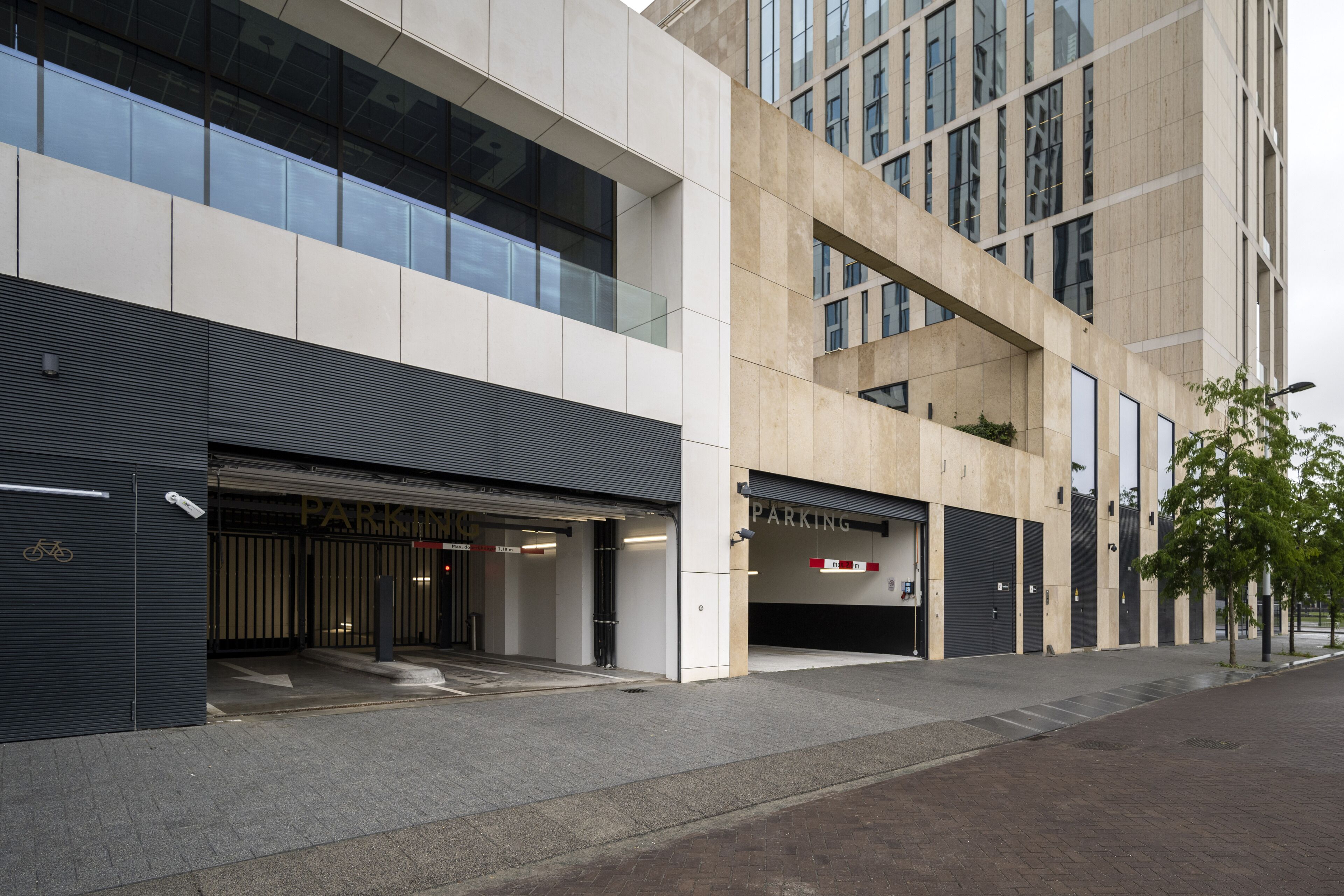 Un edificio moderno con entrada a un estacionamiento, ventanas grandes y un diseño limpio y contemporáneo.