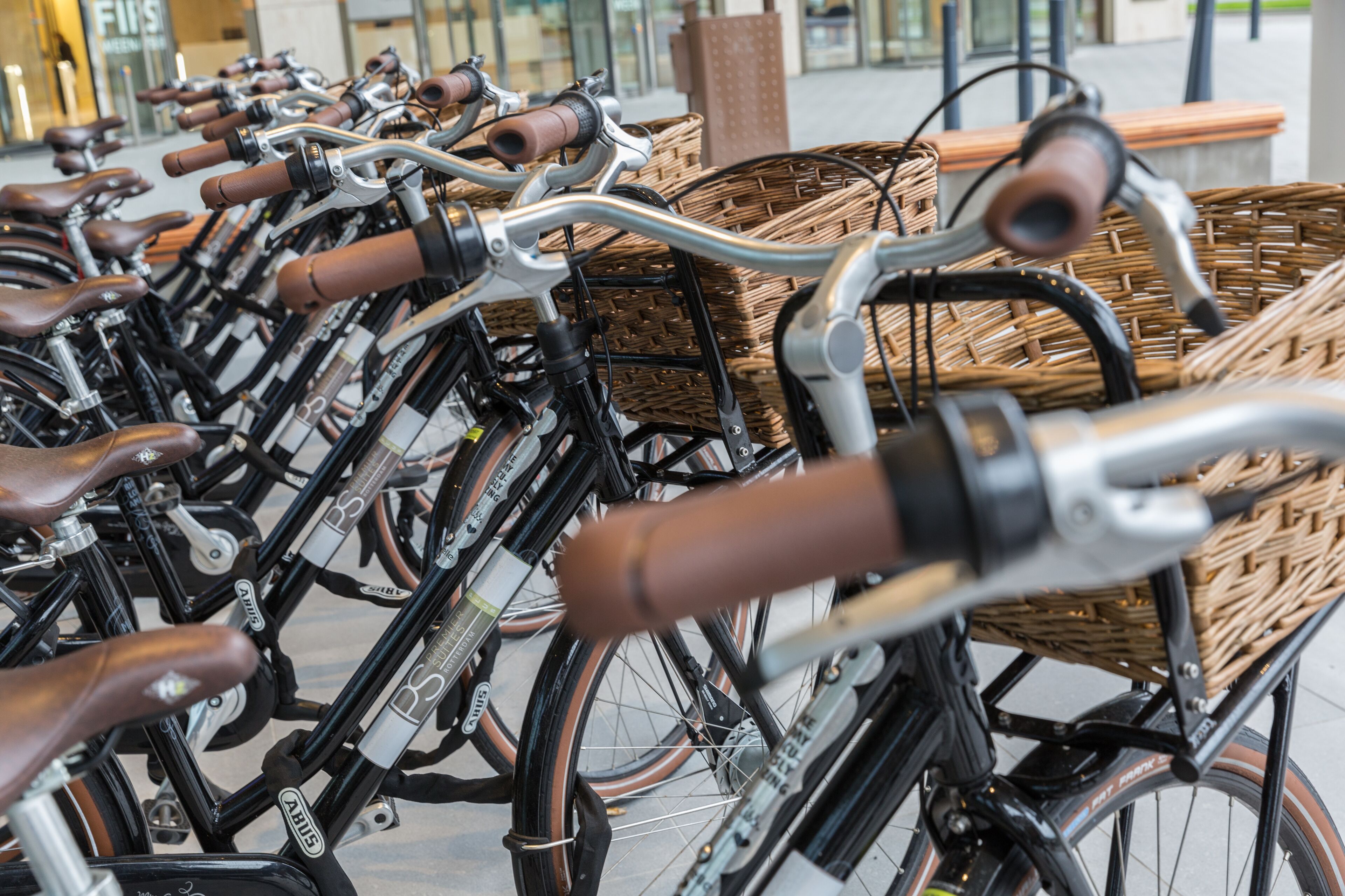 Una hilera de bicicletas con cestas de mimbre estacionadas en un espacio al aire libre.