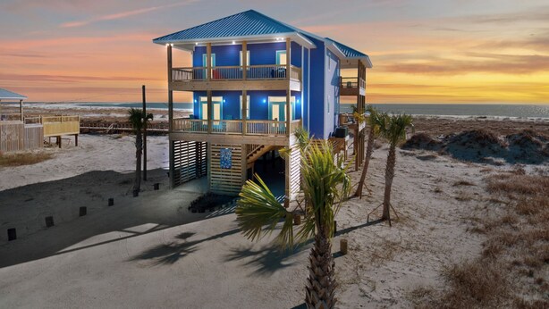 Een twee verdiepingen tellend strandhuis met een balkon en uitzicht op zee.