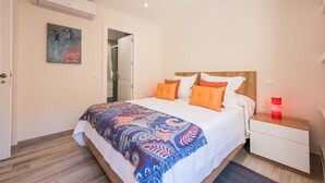 Une chambre à coucher avec un lit, une table de chevet, une lampe rouge et un tableau accroché au mur.