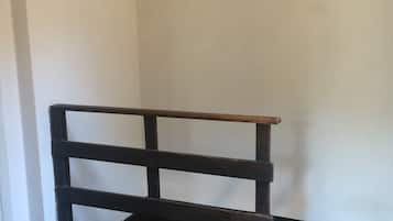 Ein Teil eines Raumes mit einer dunklen Holzbank an einer weißen Wand und einem dunklen Boden.
