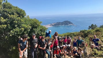 A group of people on a hiking trail with a view of the sea and a small island in the distance.