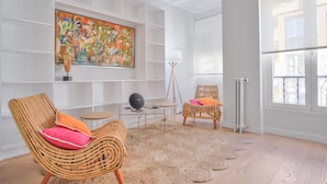 Ein Zimmer mit zwei Korbstühlen, einem großen abstrakten Gemälde und einer Stehlampe.